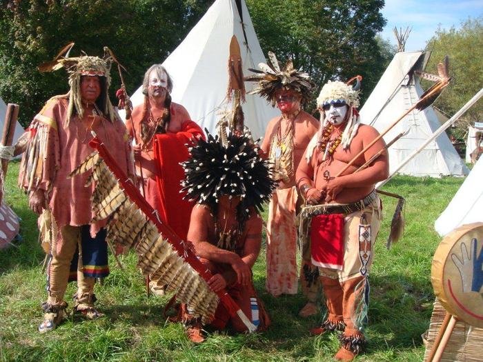 Mitglieder in Kleidung der Plains-Stämme mit Federschmuck vor Tipis